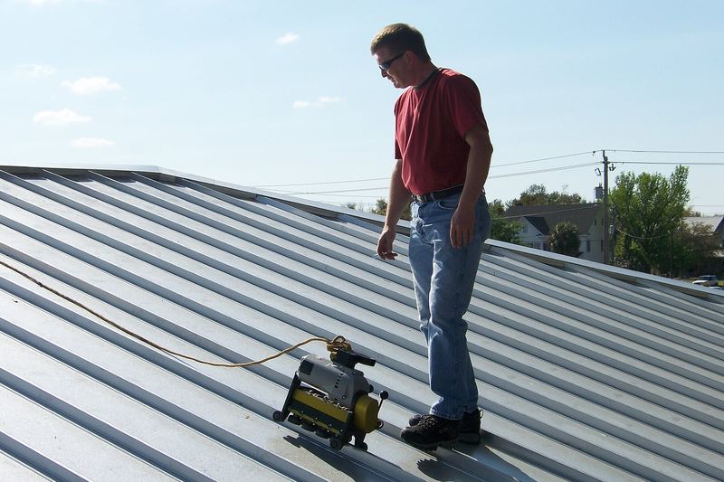 Worker using a seaming machine on a metal roof