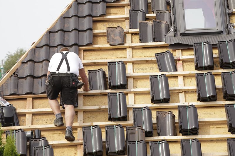 Roofer laying roof tiles on battens